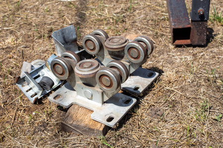 A metal roller mechanism for a sliding gate lies on the grass. gate hardware, metal parts,...