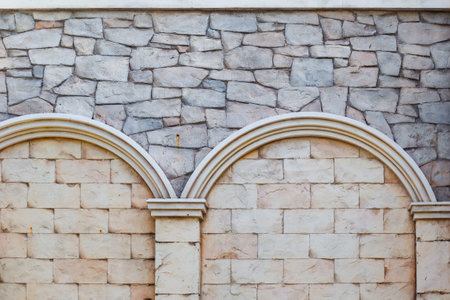 A textured stone wall features decorative arches and a combination of different masonry styles. Architectural detail, wall texture, masonry work.の写真素材