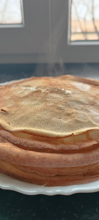 A high stack of thin golden pancakes on a plate on a dark background. pancakes stack, traditional breakfast, maslenitsa holiday. Maslenitsa.の写真素材