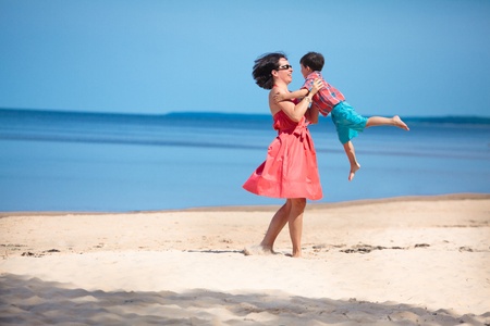 Mother and her little son playing on the beachの写真素材