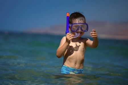 A boy in a sea with a swimming mask and snorkelの写真素材