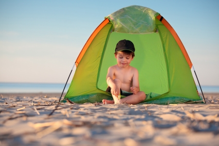 Little boy playing in his tent on the beach の写真素材