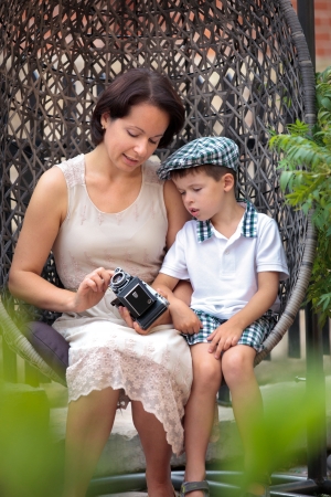 Mother and son sitting on the cane-chair and holding retro cameraの写真素材