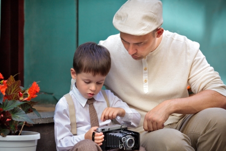 Young father and son outdoors with retro camera on their handsの写真素材
