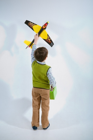 Little boy holding a plane model to aim his target let the plane fly high to the skyの写真素材