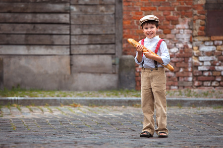 Cheerful smiling boy with baguette outdoorsの写真素材