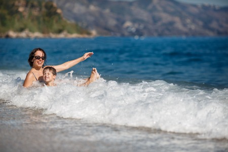 Mother and son splashing in ocean wavesの写真素材