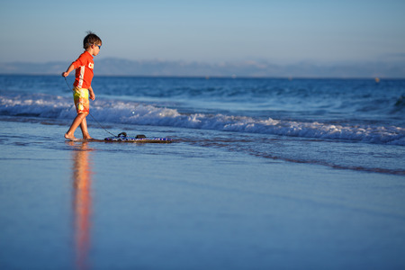 Six years old boy with surf board on exotic beachの写真素材