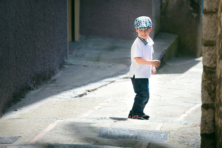 Cute little boy crossing narrow streetの写真素材
