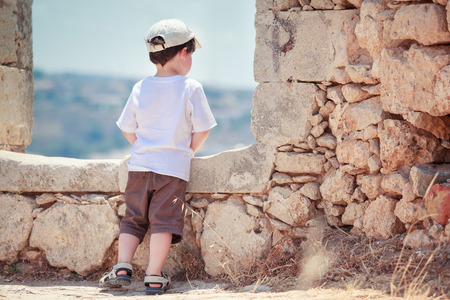 Back view of cute little boy outdoors in ancient cityの写真素材