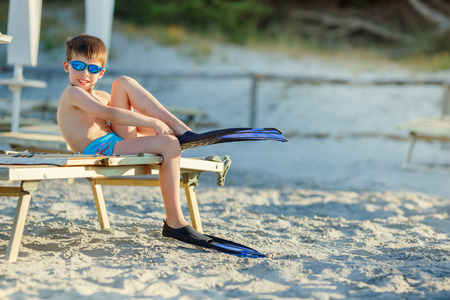 Cute little boy putting on diver flippers at tropical beachの写真素材