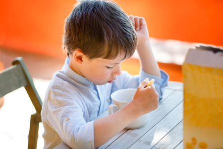 Cute little boy eating dairy breakfast outdoorsの写真素材