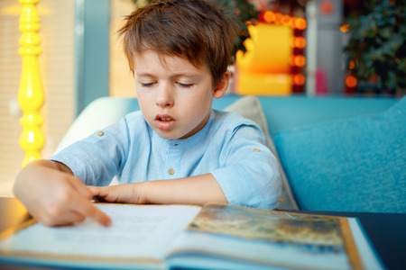 Preschooler boy reading book for elementary school