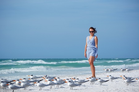 Young woman on a beach where seagulls flying - flock of birds, Siesta Key beach, Floridaの写真素材