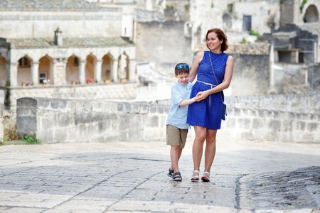 Young mother and her little son walking outdoors in cityの写真素材