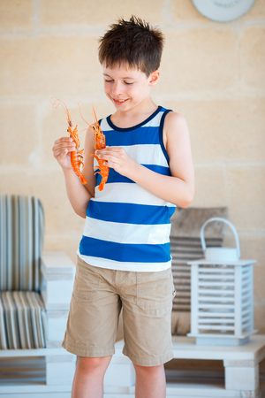 Cute little boy holding big prawn in hands for today's mealの写真素材