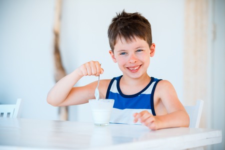 Portrait of smiling little boy eating delicious yogurtの写真素材