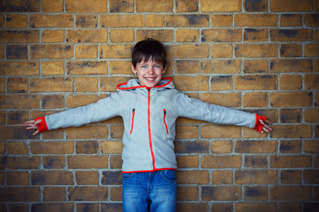 Portrait of cute little boy near brick wall outdoorsの写真素材
