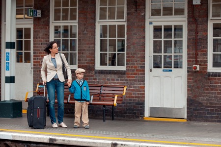 Young mother and son waiting for train on railway stationの写真素材