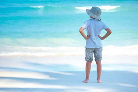 Back view of playful little boy on white sand beach during summer vacationの写真素材