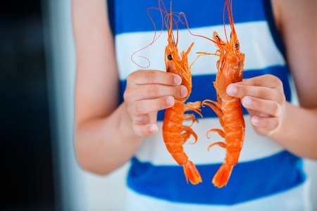 Close up of kid hands with cooked shrimpsの写真素材