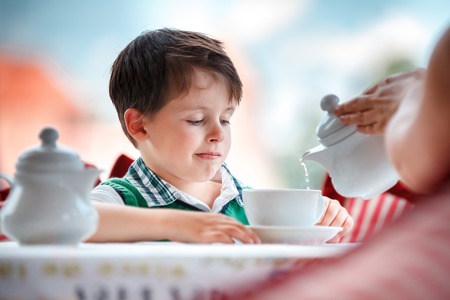 Cute little boy drinking tea in cafeの写真素材