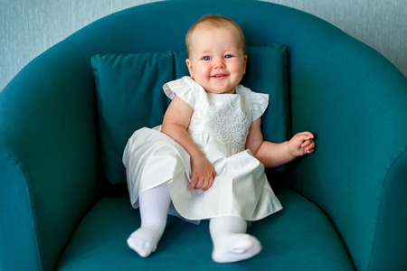 Portrait of happy little child wearing white dress in casual clothes posing indoorsの写真素材