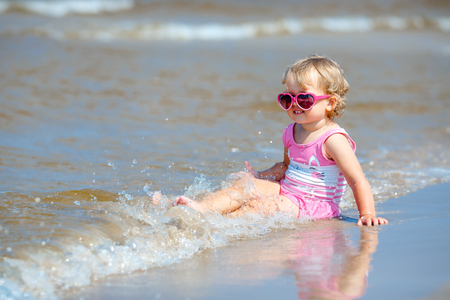 Adorable toddler girl splashing in ocean wavesの写真素材