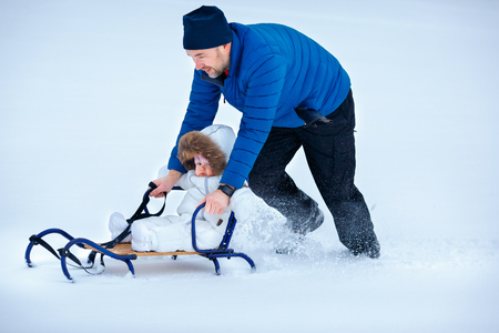 Adorable baby girl enjoying sledding. Father sledding his little daughterの写真素材