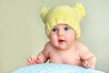 Portrait of a cute newborn baby girl in yellow knitted hat posing on big ballの写真素材