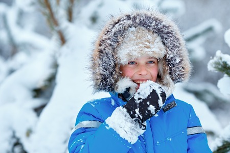 Cute little boy wearing warm clothes playing on winter forestの写真素材