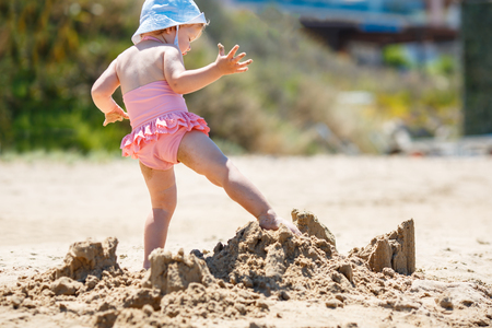 Child playing on tropical beach. Little girl digging sand at sea shore. Travel with young childrenの写真素材