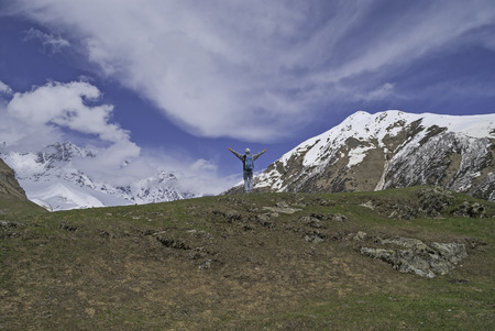 Young man arms outstretched to the side at the foot of Mount Shkhara, Georgia