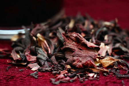Dry pomegranate leaves lie near a mug with brewed pomegranate tea on a burgundy knitted backgroundの写真素材
