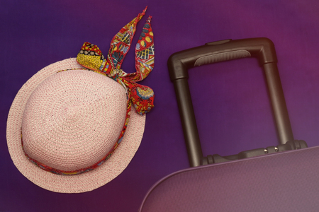 Hat and a suitcase on a lilac background tourism travel hat pink with a bandage fly away on a journey collect thingsの写真素材