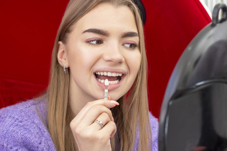 teeth whitening procedure girl pick up the shade of teeth looking in the mirror