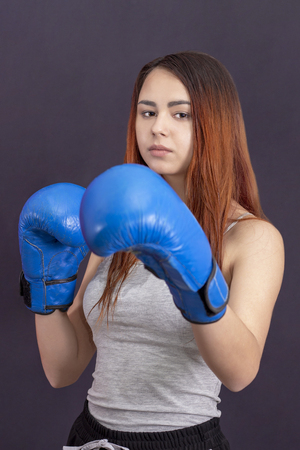boxer girl in blue boxing gloves in a gray t-shirt in the rackの写真素材