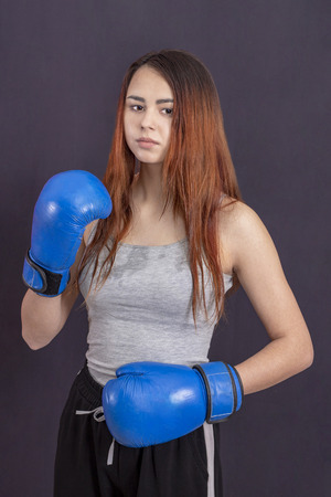 boxer girl in blue boxing gloves in a gray t-shirt in the rackの写真素材
