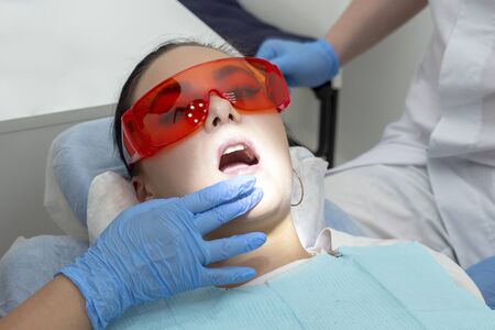 girl on examination at the dentist. treatment of carious tooth. the doctor uses a mirror on the handle and a boron machineの写真素材