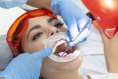 girl on examination at the dentist. treatment of carious tooth. the doctor uses a mirror on the handle and a boron machineの写真素材