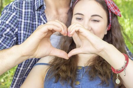 young couple making a heart with hands. meeting love summer picnicの写真素材