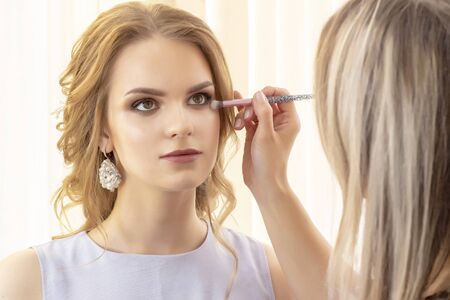 make-up artist applies beautiful models of shadow and concealer on the eyelids and faceの写真素材