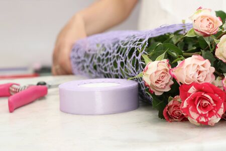 florist girl working in a flower shop. Soft shades of fresh spring flowers, wrapped in decorative paper. Floristry business. Floristry courses. Learn to master the art of ikebana. Florist shares her skills showing how to arrange flowers in a perfect beautiful bouquetの写真素材