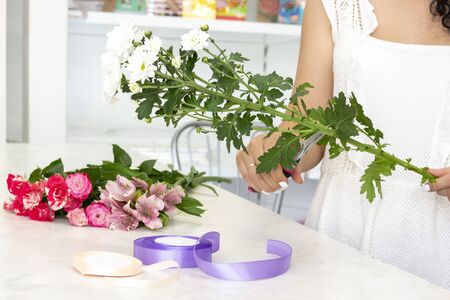 business, sale and floristry concept - close up of florist woman holding bunch at flower shop. Soft shades of fresh spring flowers. の写真素材