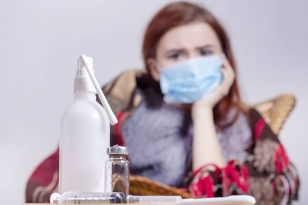 woman with sneezing nose blowing in tissue suffering winter cold and flu virus symptoms having medicines tablets and pills in illness and domestic health care conceptの写真素材