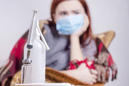 woman with sneezing nose blowing in tissue suffering winter cold and flu virus symptoms having medicines tablets and pills in illness and domestic health care conceptの写真素材