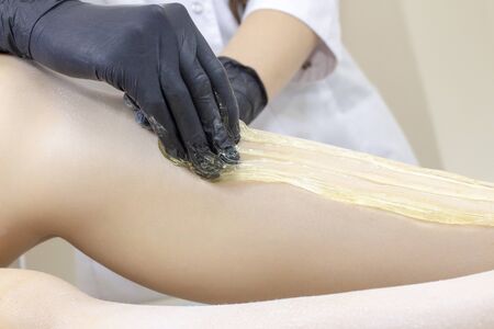 Beautician depilating womans legs with liquid sugar in spa center. Depilation Of Legs With Sugar Paste.の写真素材