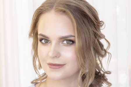 beautiful girl with a wedding hairstyle looks at herself in the mirror, portrait of a young girl. beautiful make-up. beauty saloonの写真素材
