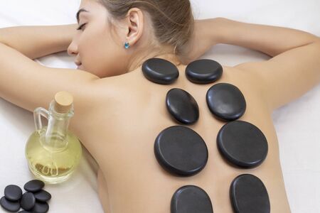 Spa Hot Stone Massage. Stone treatment. Woman getting a hot stone massage at a day spa. beautiful girlの写真素材