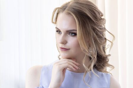 beautiful girl with a wedding hairstyle looks at herself in the mirror, portrait of a young girl....